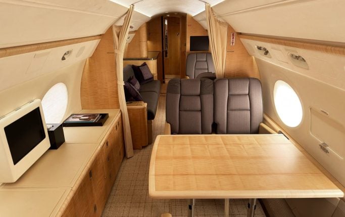 Cabin seating with dark gray seats and light wood trim.