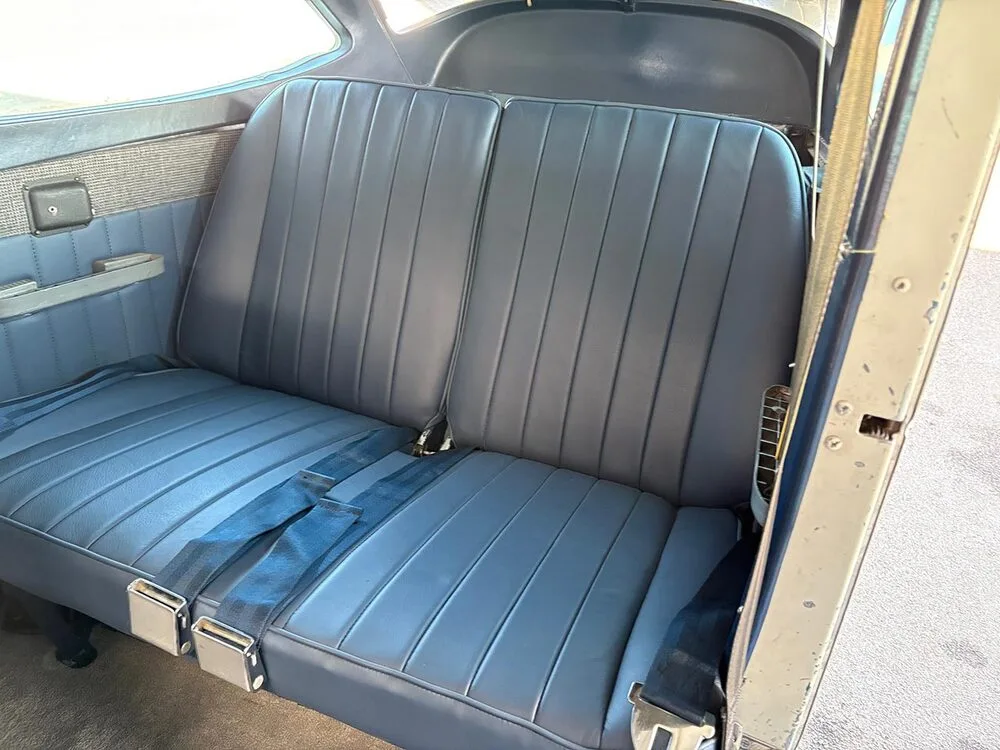 The blue upholstered rear passenger seats with seatbelts inside a small aircraft cabin.
