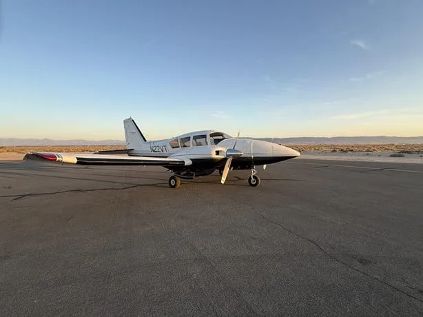 A silver and black single-engine aircraft, N22VT, is parked on an asphalt runway at sunset.