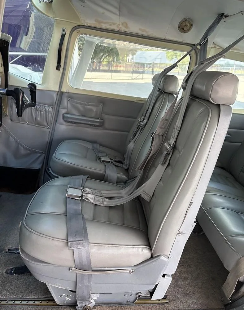 Interior view of the gray passenger seats and cockpit controls from the rear of the aircraft cabin.