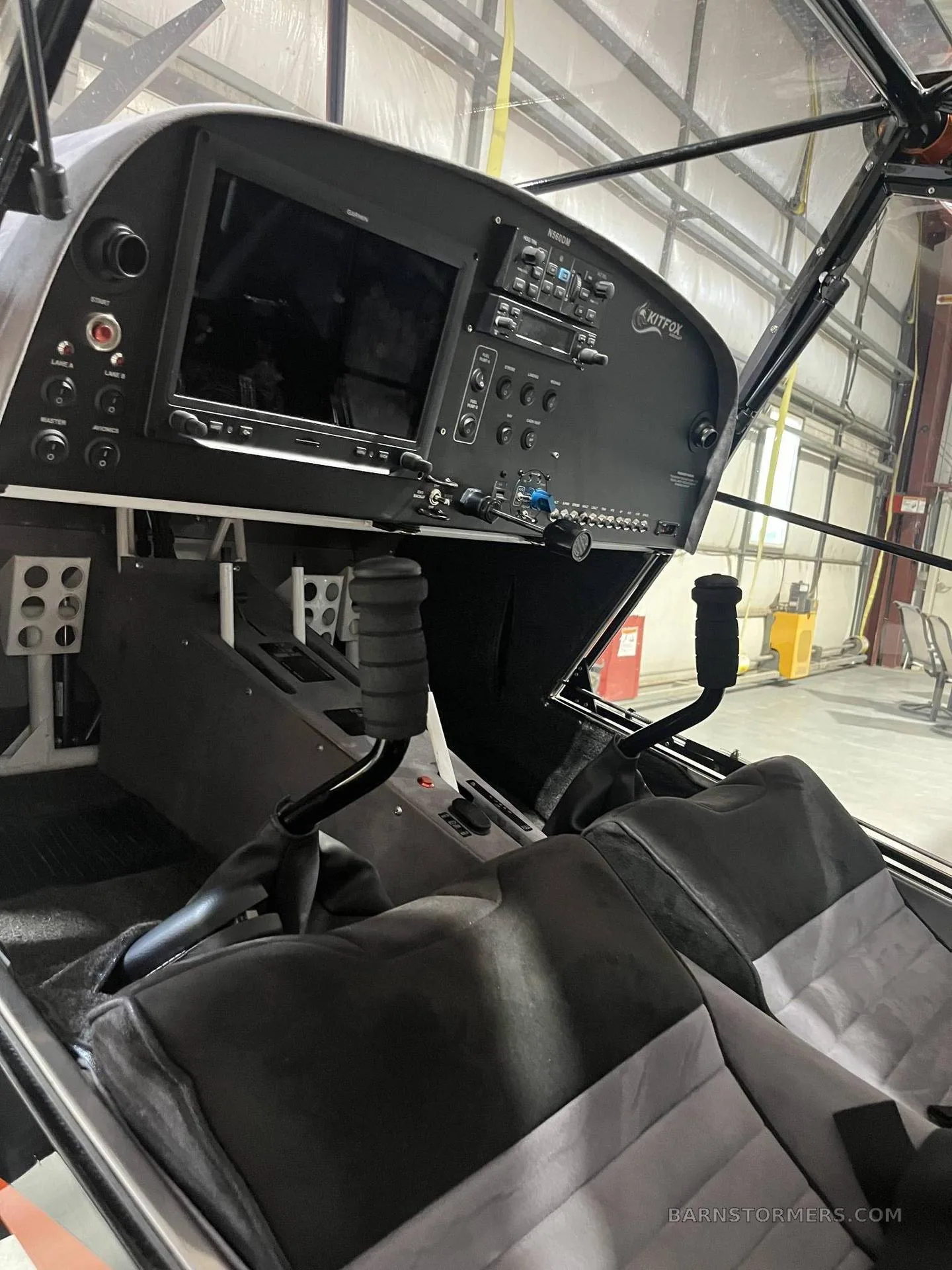The cockpit of a Kitfox S7 Super Sport aircraft, showing the instrument panel with a large display, controls, and pedals.