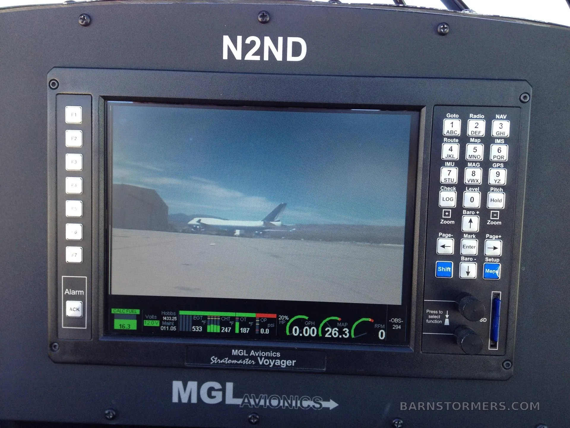 A close-up of an MGL Avionics StratoMaster Voyager display in a cockpit, showing a view of a large aircraft on an airfield.