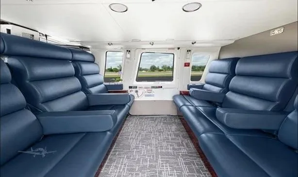 The helicopter's interior cabin features two rows of plush blue leather seats facing each other, with a patterned carpet.