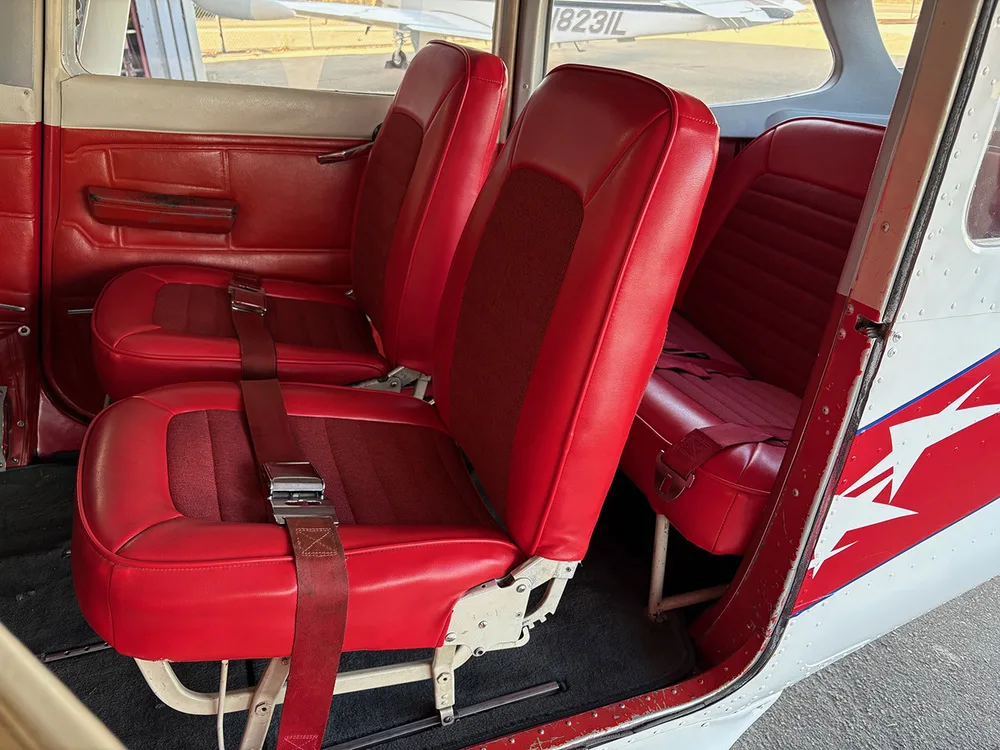 The red interior cabin seats of the aircraft, viewed from the open door.