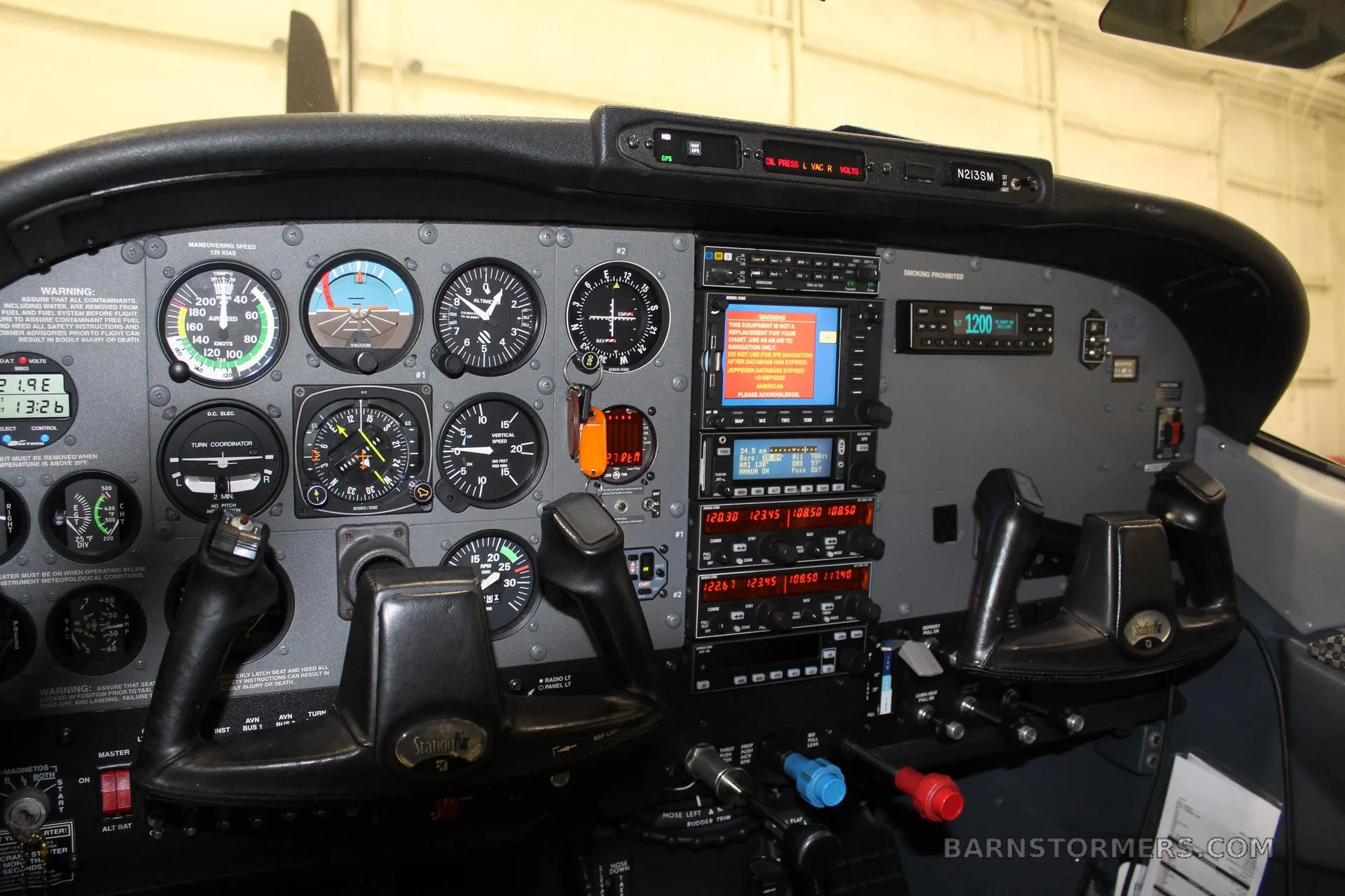 A detailed view of a small aircraft cockpit with analog gauges, modern digital displays, and dual yokes.