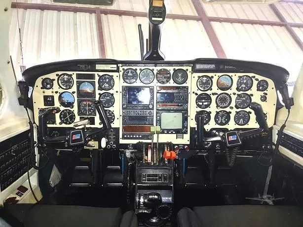 The cockpit of an aircraft, featuring a detailed instrument panel with numerous analog gauges and some digital screens.