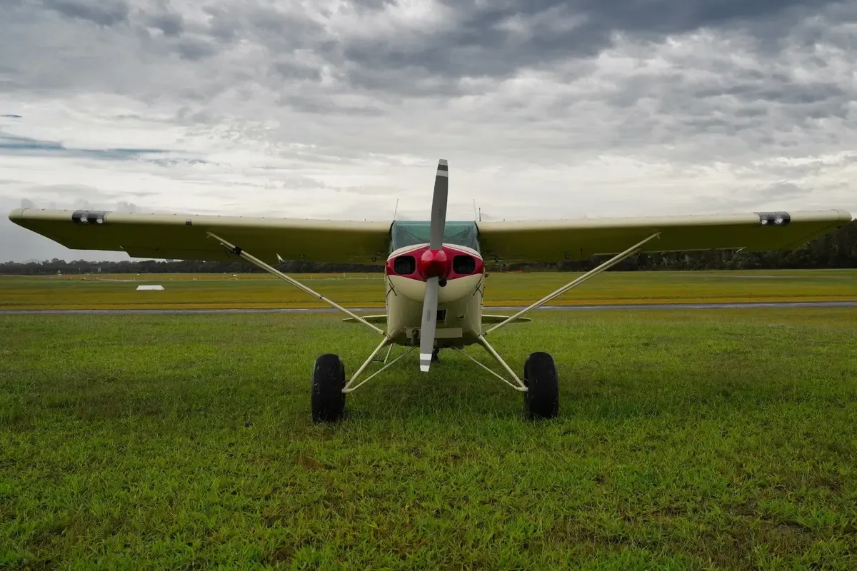 A cream and maroon single-engine taildragger aircraft with registration VH-TSY parked on a grassy airfield, viewed from the front.