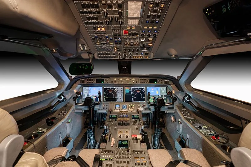 The cockpit of a business jet with multiple digital displays and numerous buttons and switches.
