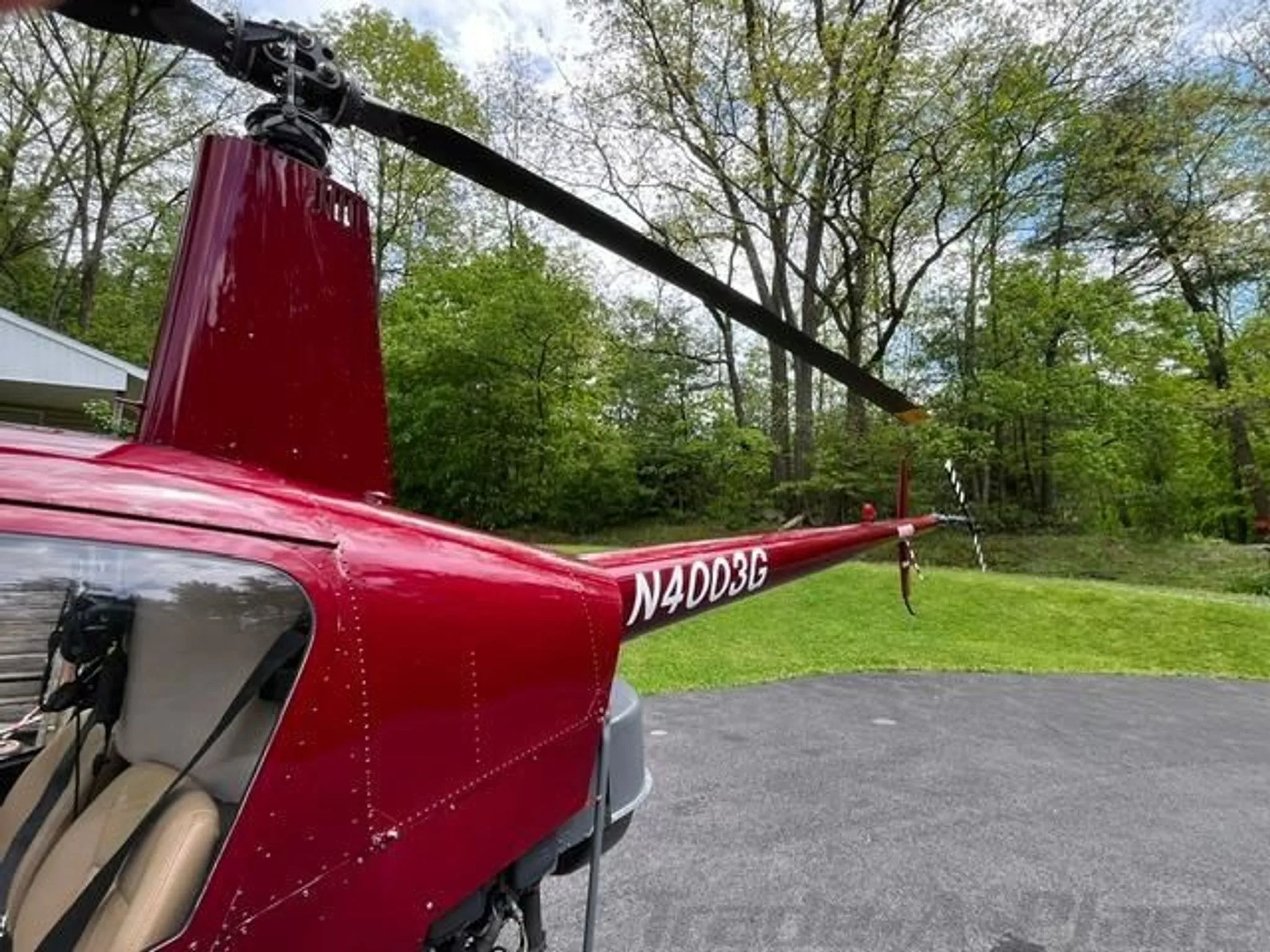 A rear-side view of a red helicopter with registration N4003G, showing the tail rotor and main rotor.