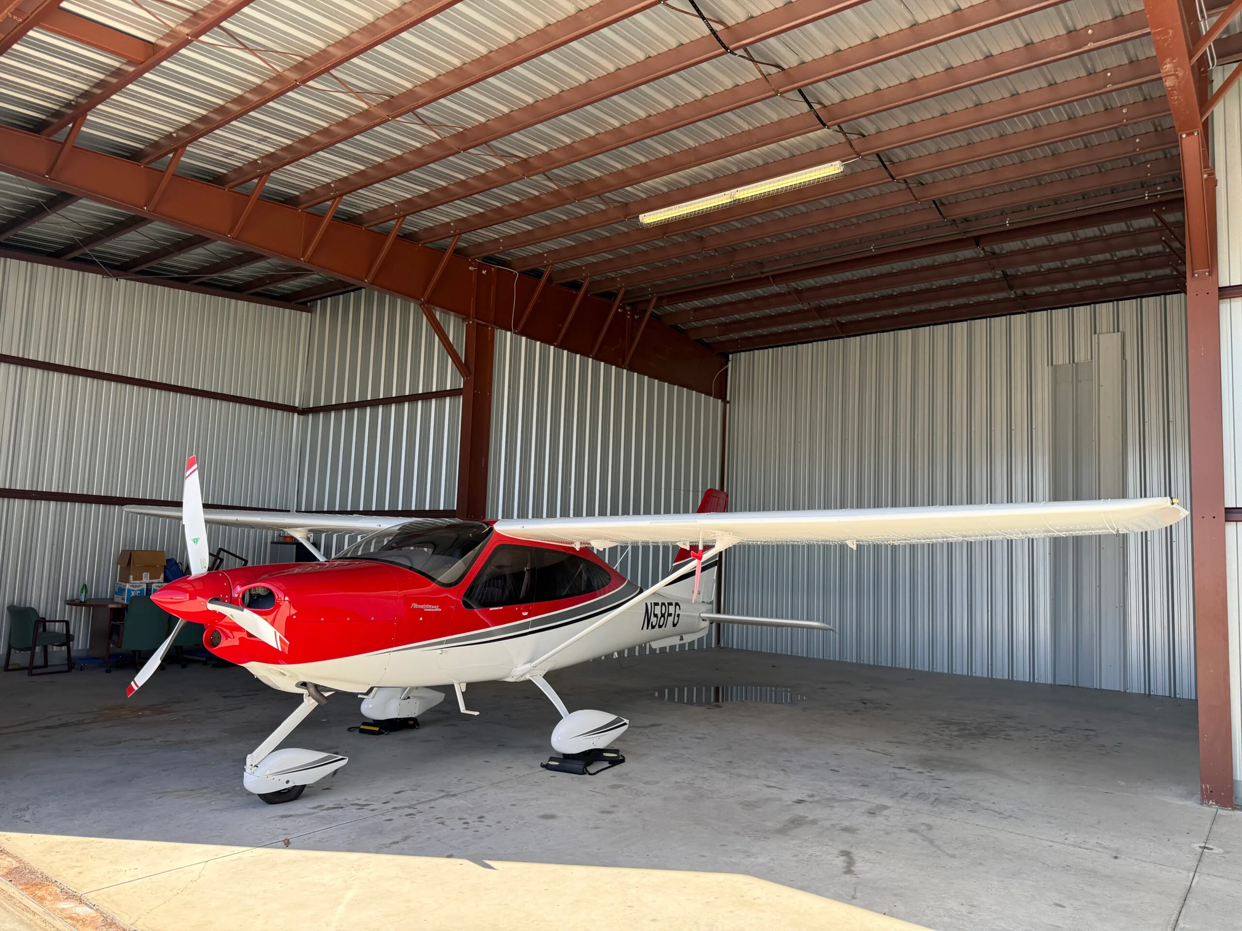 Tecnam P2010 aircraft N58FG parked in a hangar with a red and white paint scheme.
