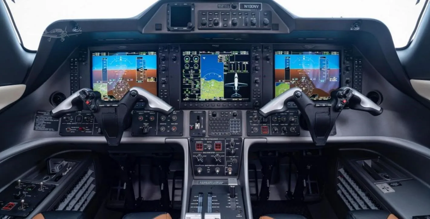 The modern glass cockpit of an Embraer Phenom 100, showing multiple digital displays and controls.