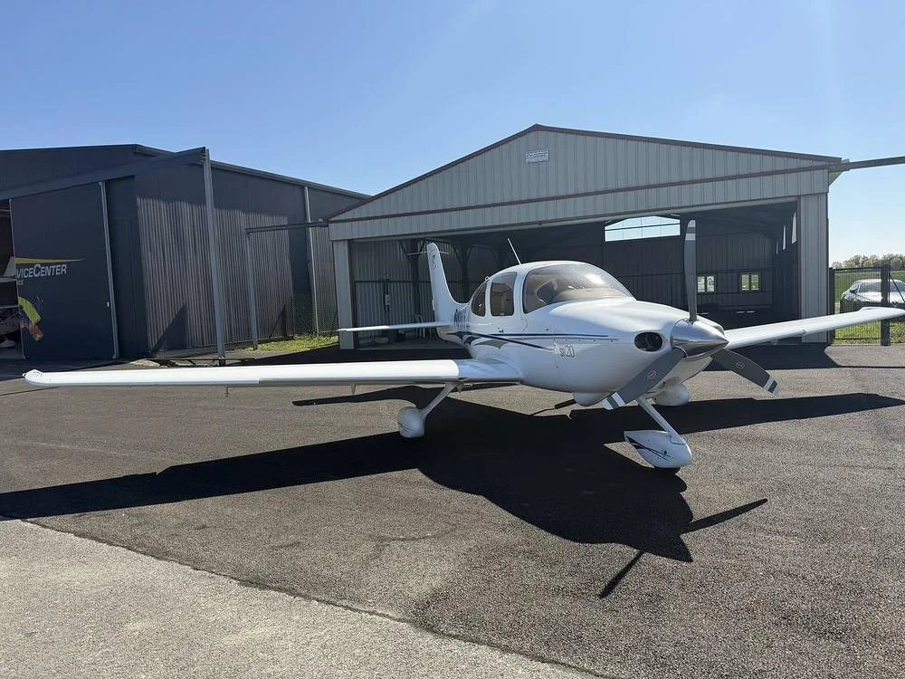 A Cirrus SR20 parked in front of a hangar.