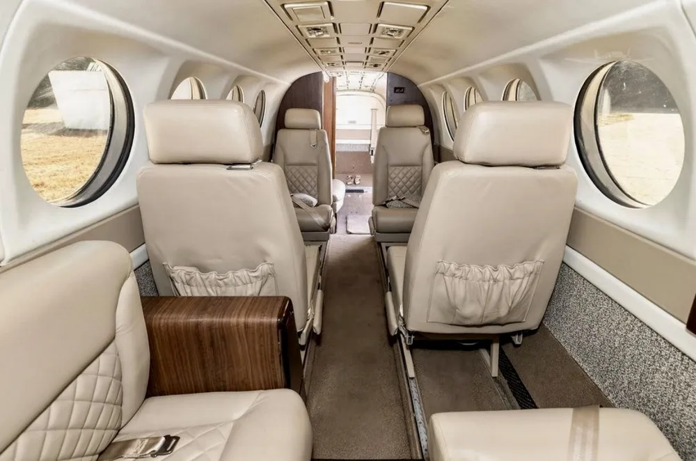 The interior cabin of an aircraft featuring beige leather seats and wood accents.