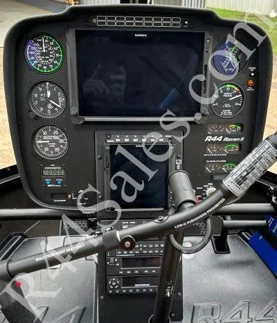 The cockpit of a Robinson R44 Raven II helicopter features a Garmin display and analog gauges.