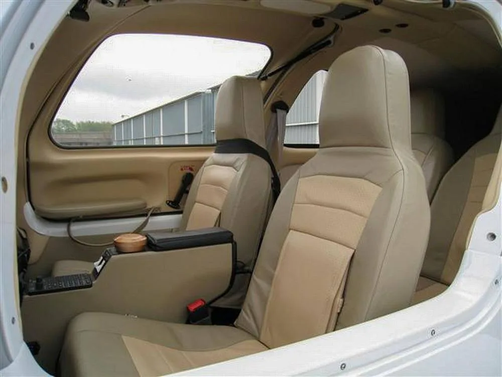 The tan and beige leather interior cabin seats of a small aircraft, viewed from the rear.