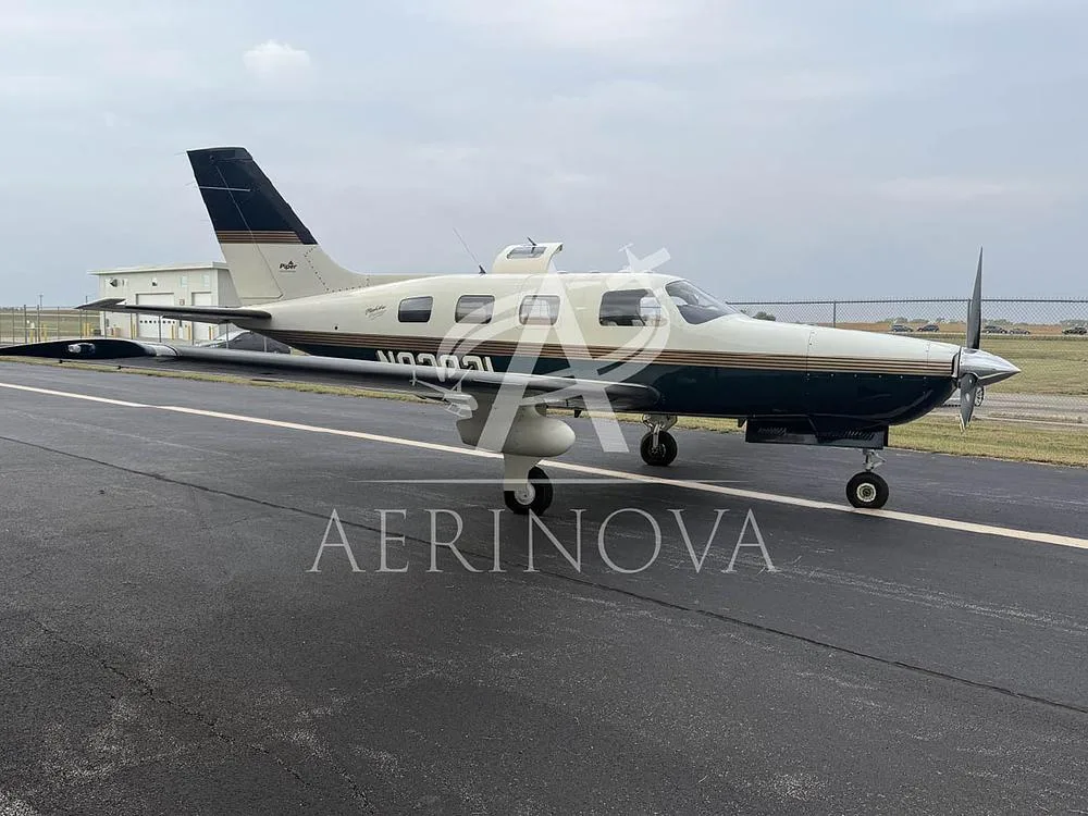 A Piper Malibu Mirage N92821 in dark green and cream paint scheme on an airfield under a cloudy sky.