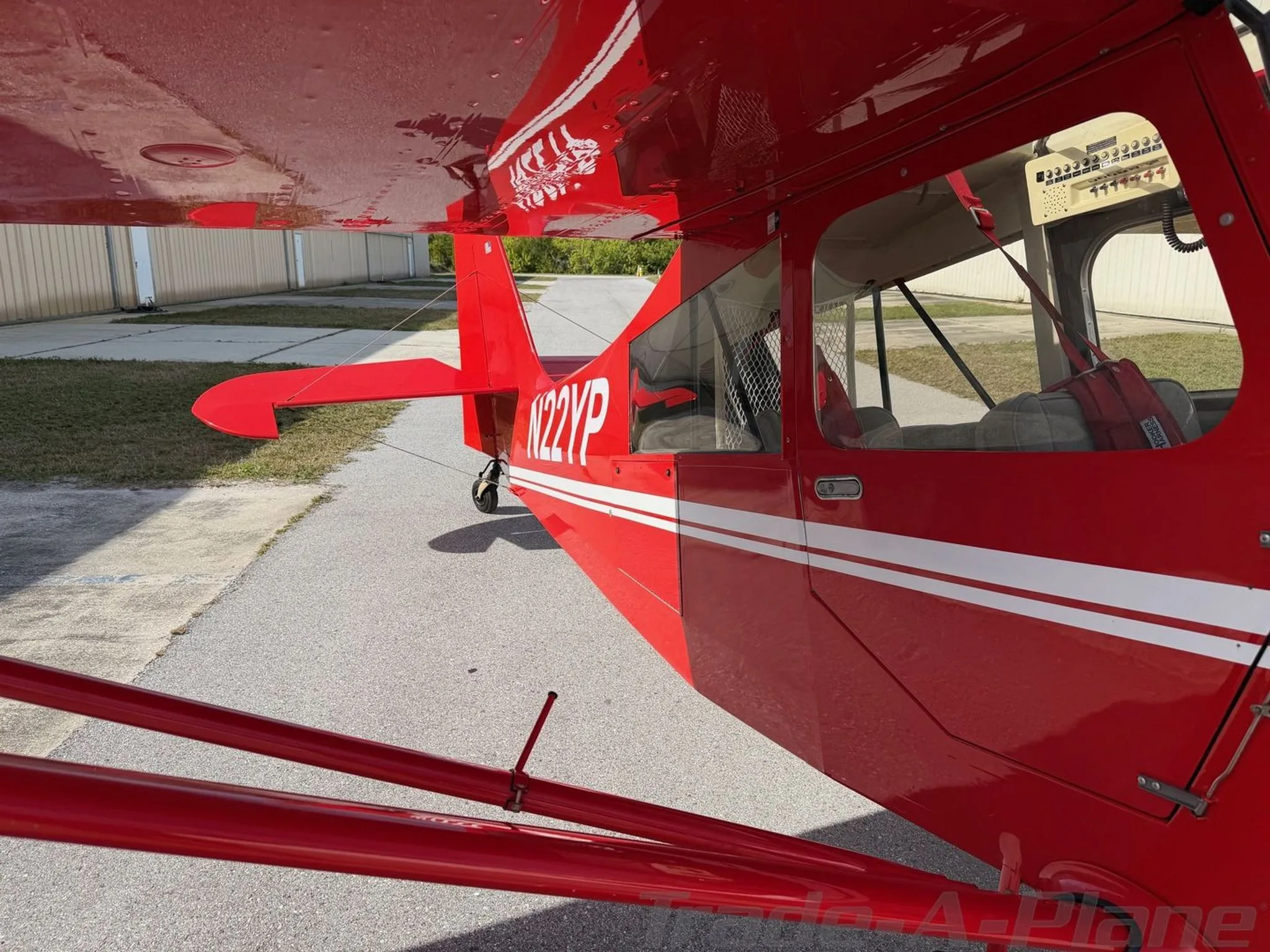 A side view of the red American Champion Xtreme Decathlon, highlighting the N22YP registration on the tail and the cabin windows.