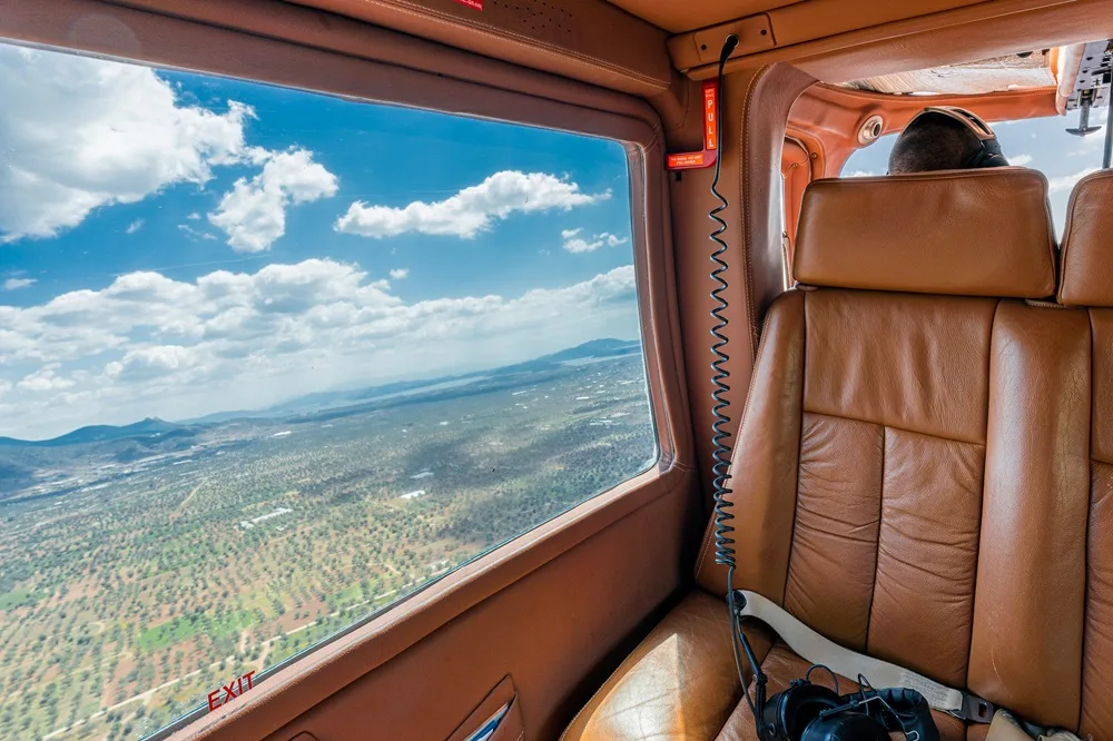 Interior view of the helicopter cabin with a view of the landscape outside the window.