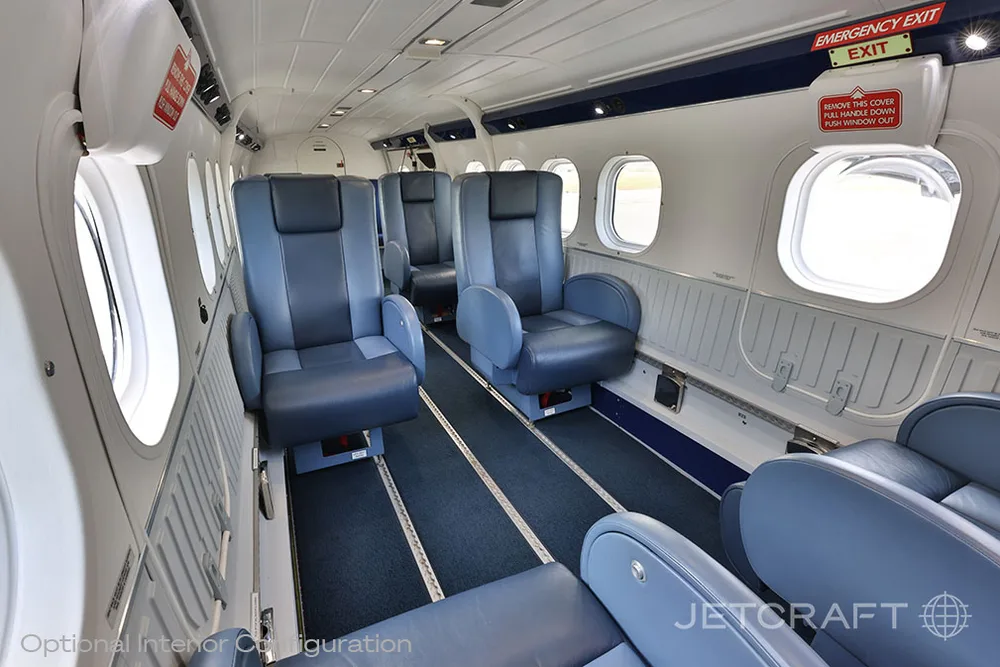 An aircraft interior with blue leather seats, an aisle, and emergency exit signs.