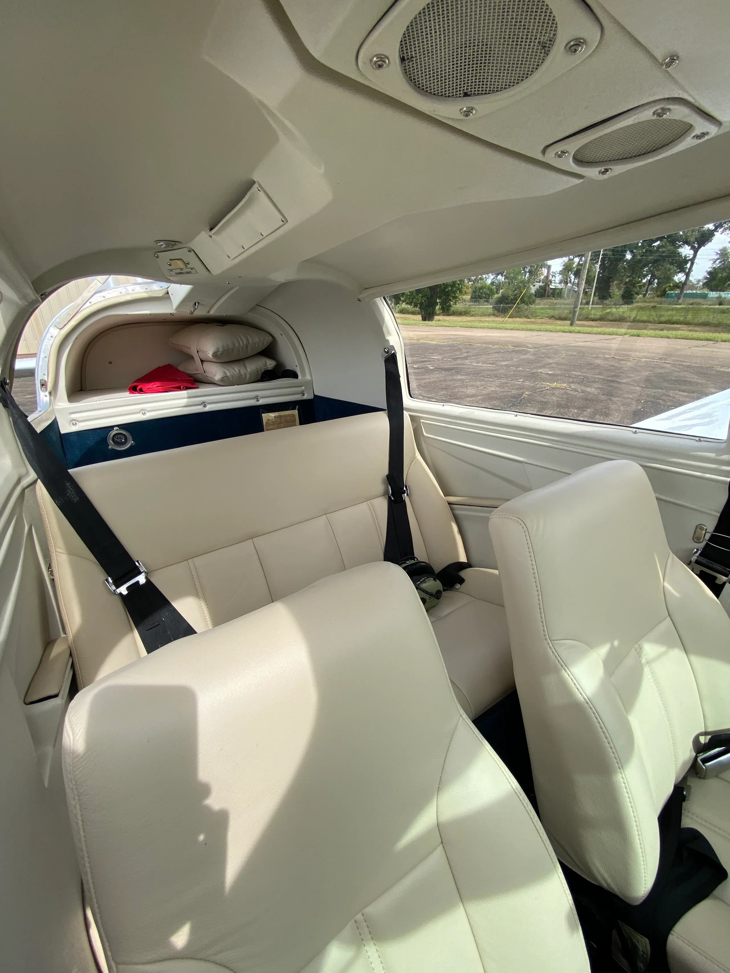 View of the cream-colored leather passenger seats and rear cargo area inside the aircraft cabin.