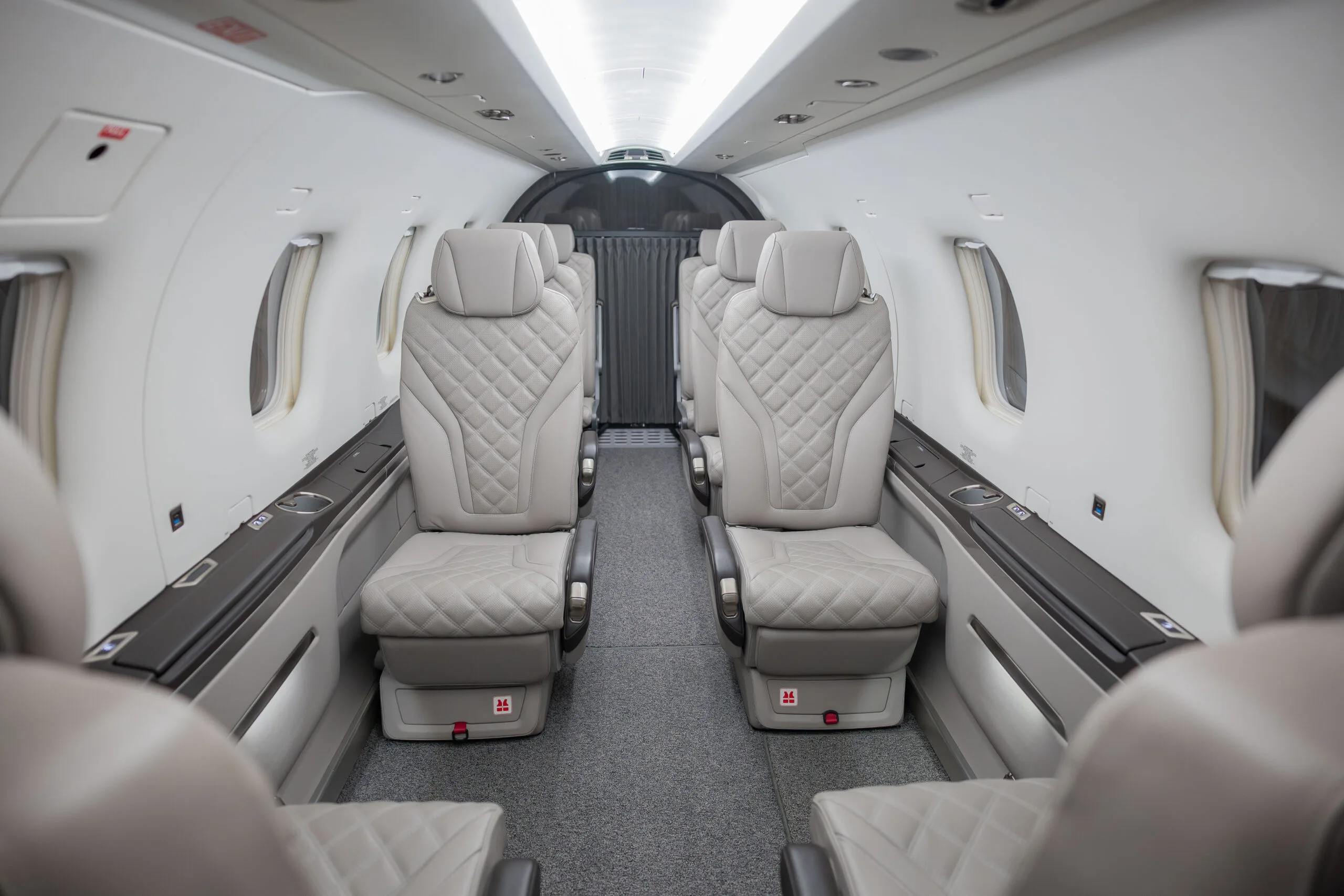 The light grey leather interior cabin of a Pilatus PC-12 aircraft, showing quilted seats facing forward.
