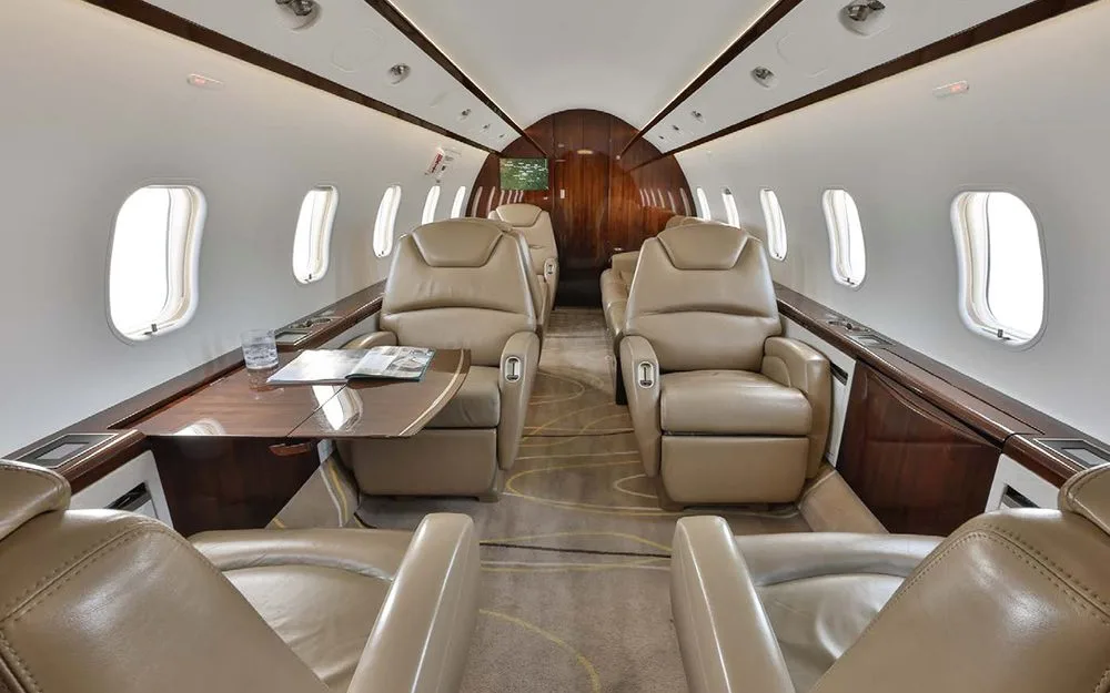 A long view of the aircraft's interior cabin, showing multiple tan leather seats and a central aisle.