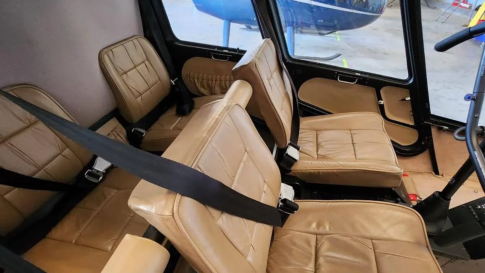 The tan leather seats of a helicopter cabin, viewed from the front.
