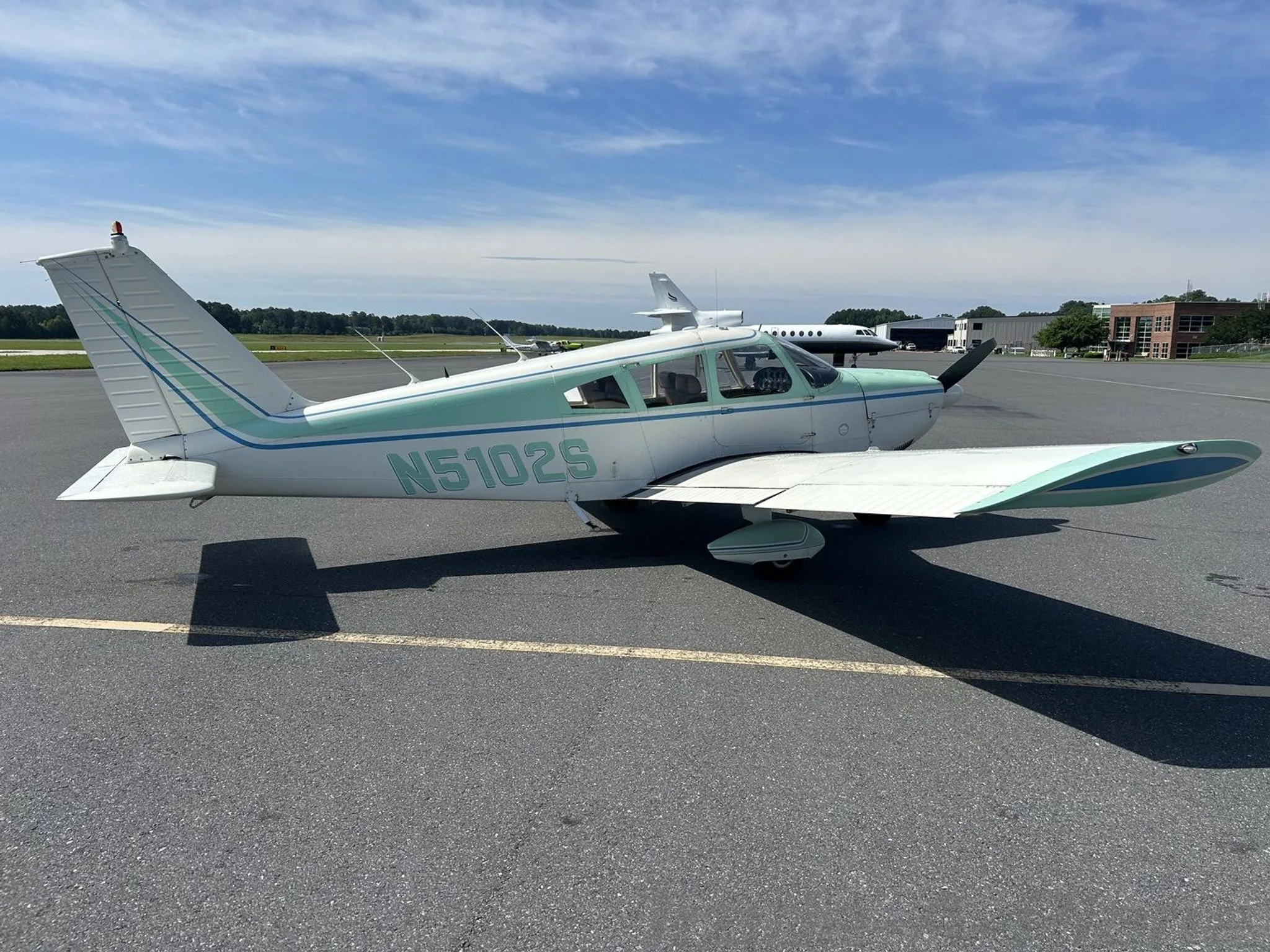 A side view of the Piper Cherokee 180 on the tarmac.