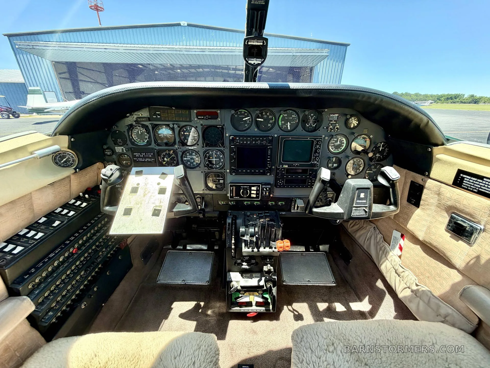 The cockpit of a twin-engine aircraft features a complex instrument panel with analog gauges and digital displays, and dual yokes.