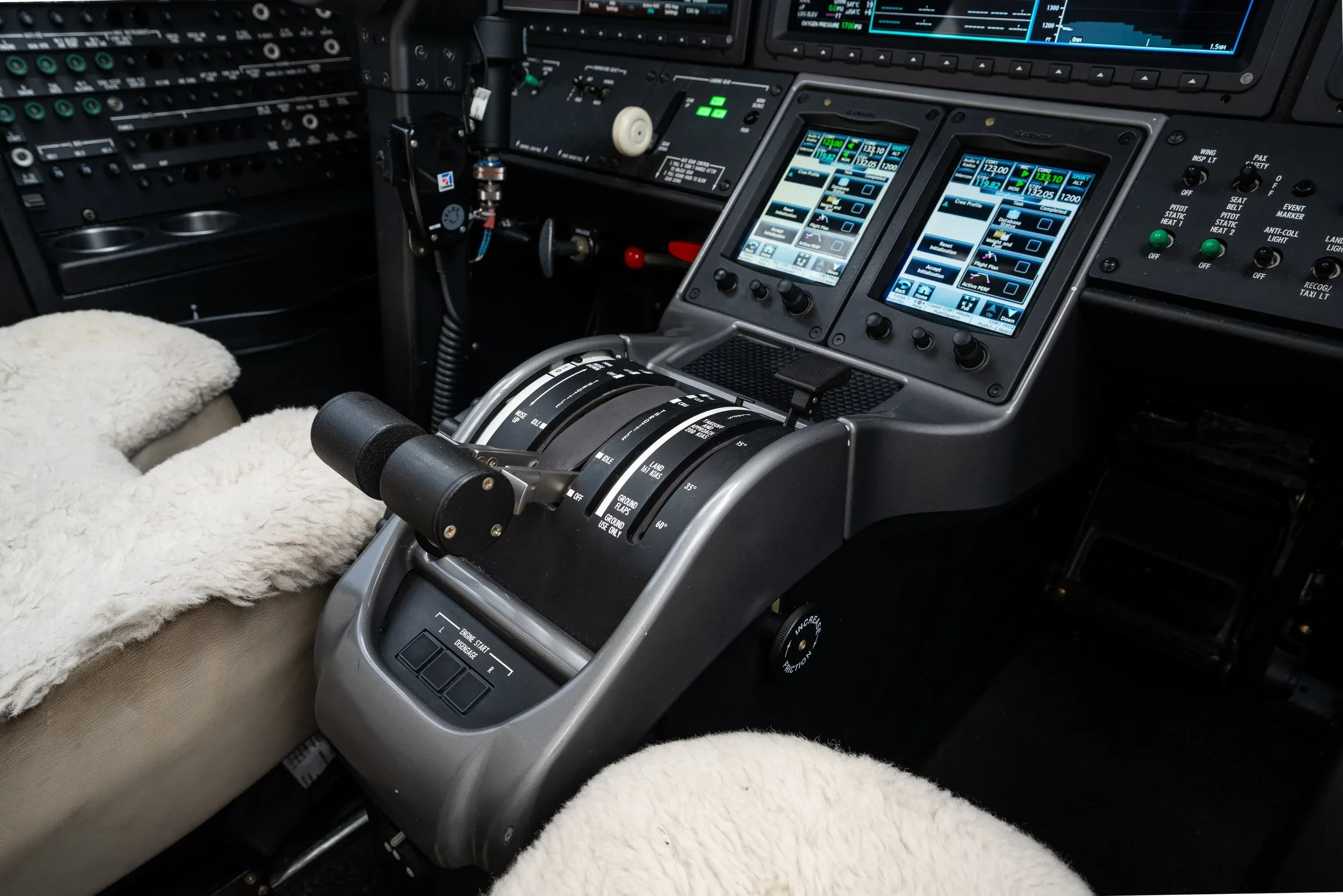 Close-up view of the throttle quadrant and lower instrument panel with two display screens in an aircraft cockpit.