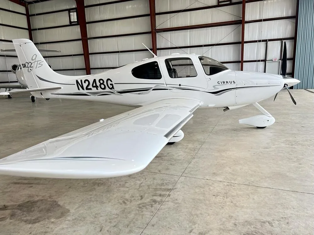 A side view of a white Cirrus SR22 aircraft with registration N248G, parked in a hangar.