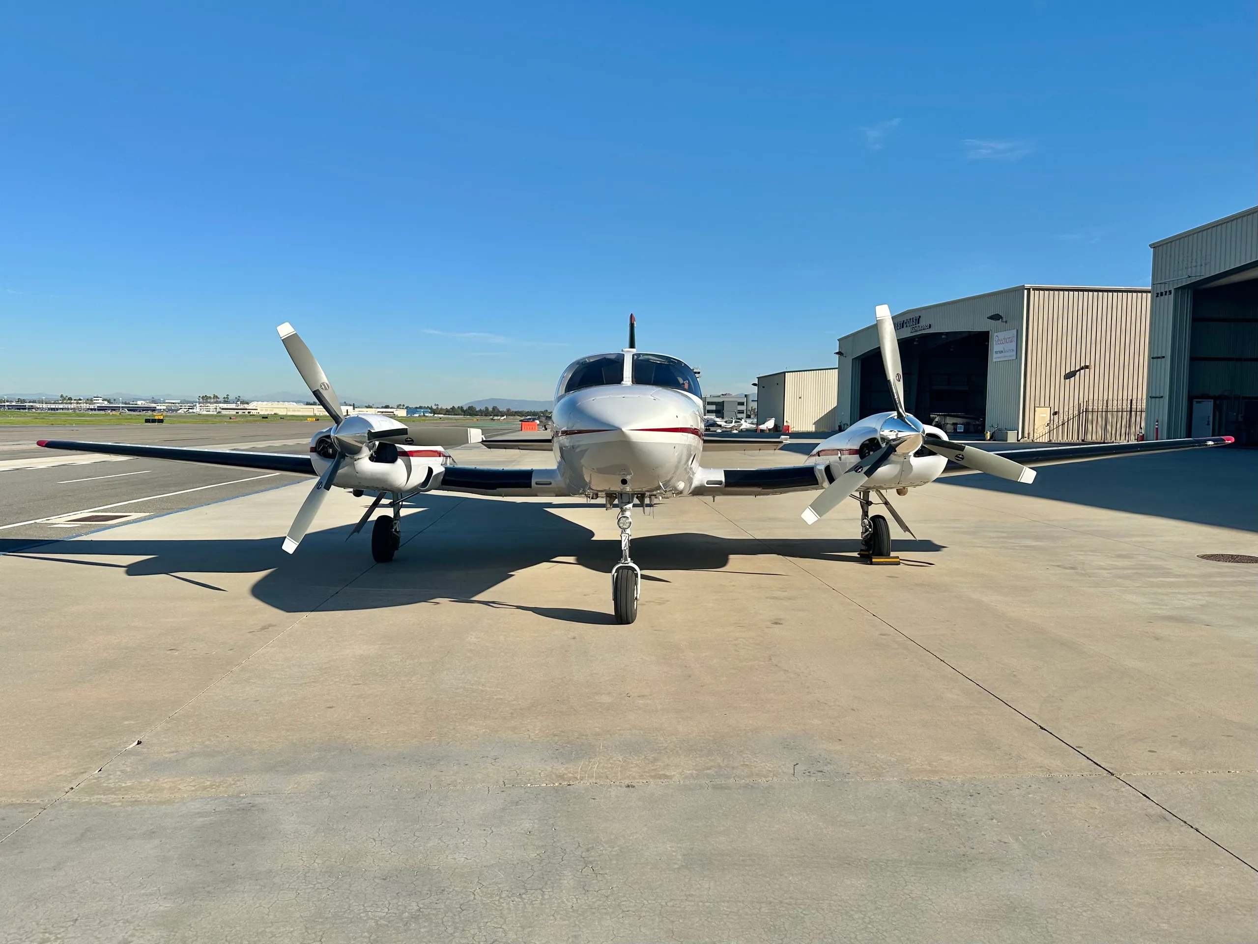 A front view of a white and maroon Cessna 421 Golden Eagle II parked on an airfield.