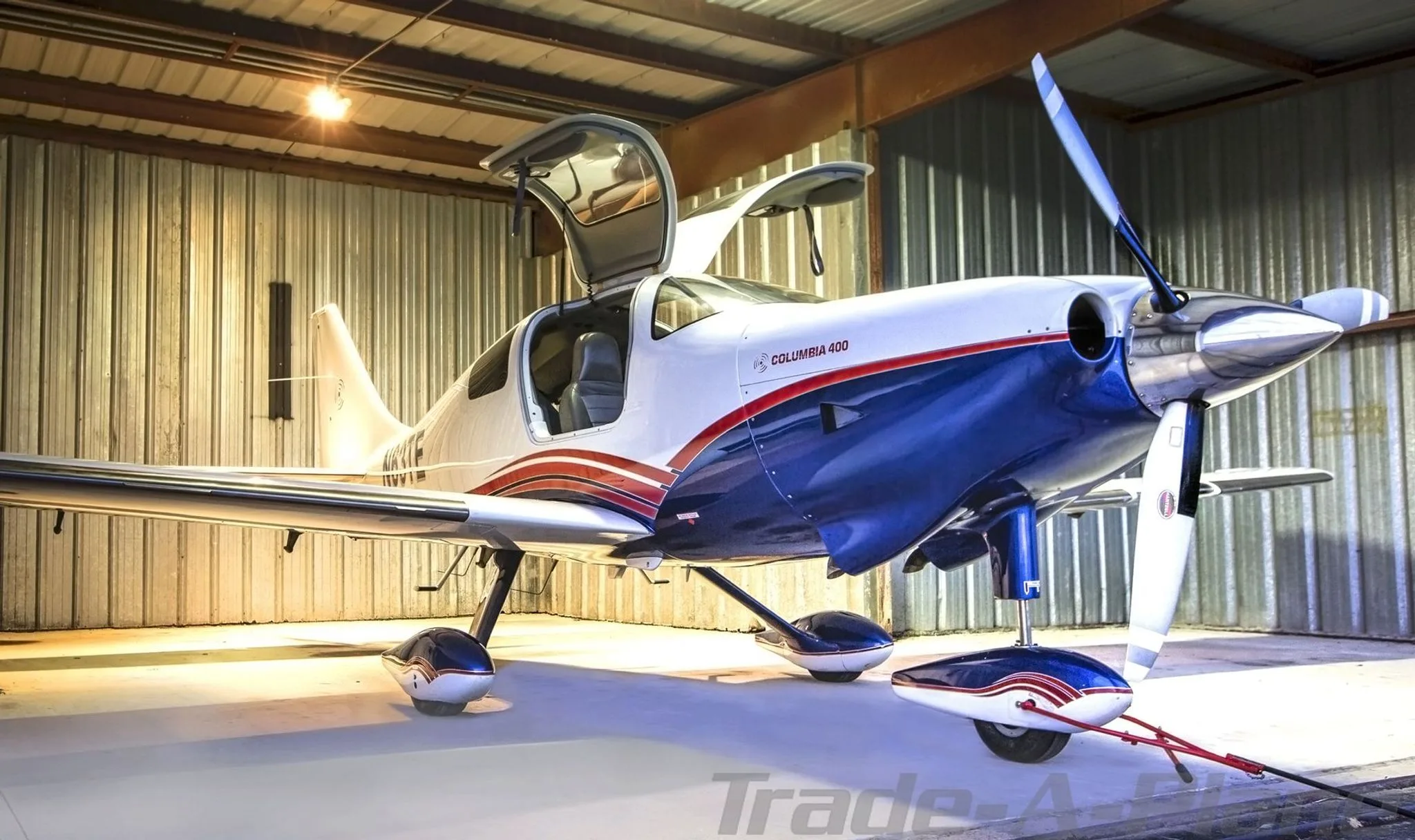 Front-right view of a white and blue Columbia 400 with open doors inside a hangar.