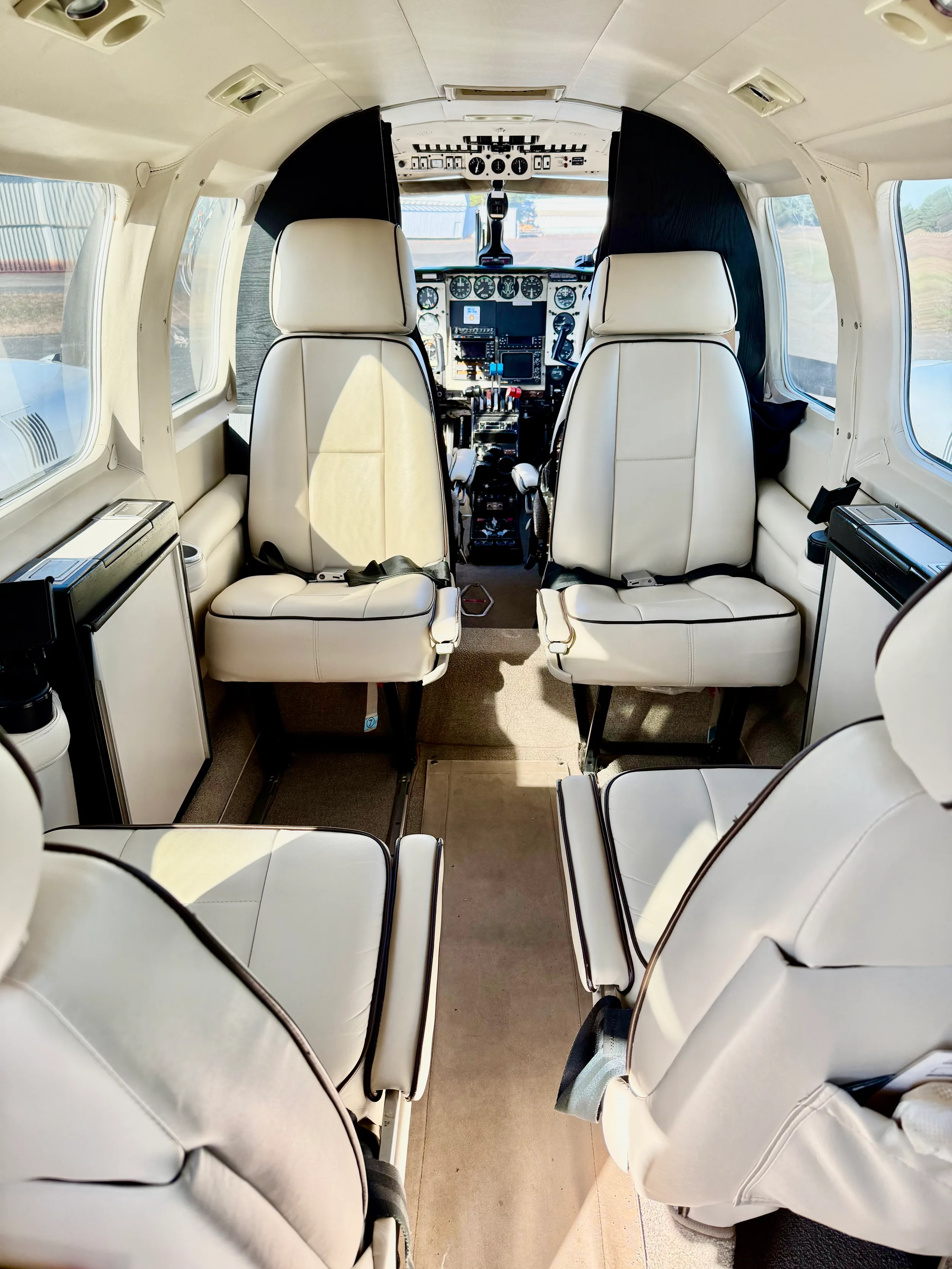 The aircraft's interior cabin with cream-colored leather seats and a view into the cockpit.