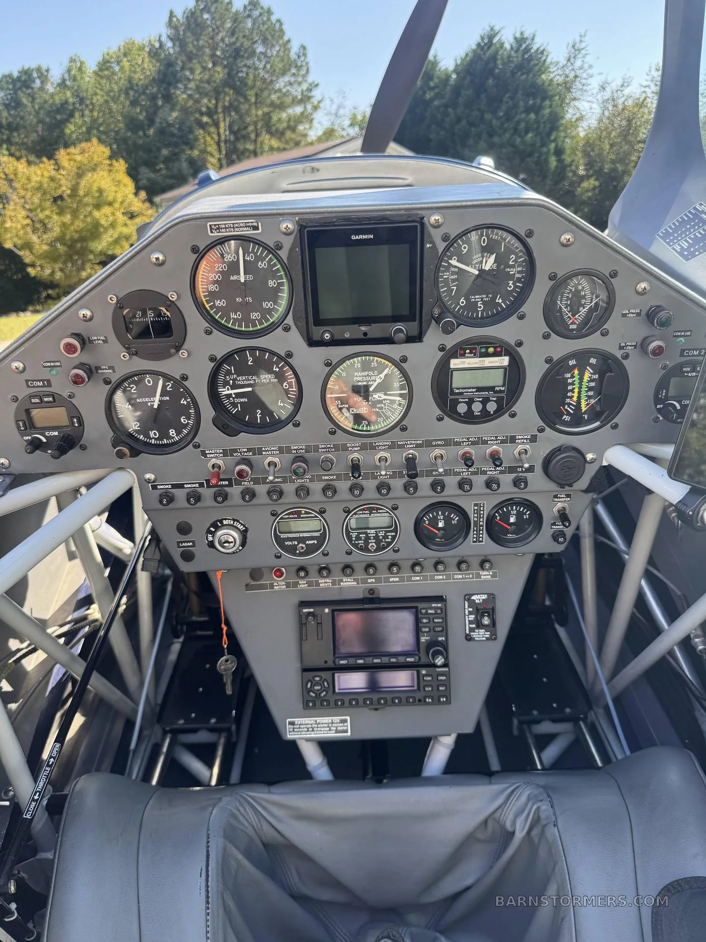 The detailed instrument panel of an aircraft, featuring various analog gauges, a Garmin display, and radio controls.