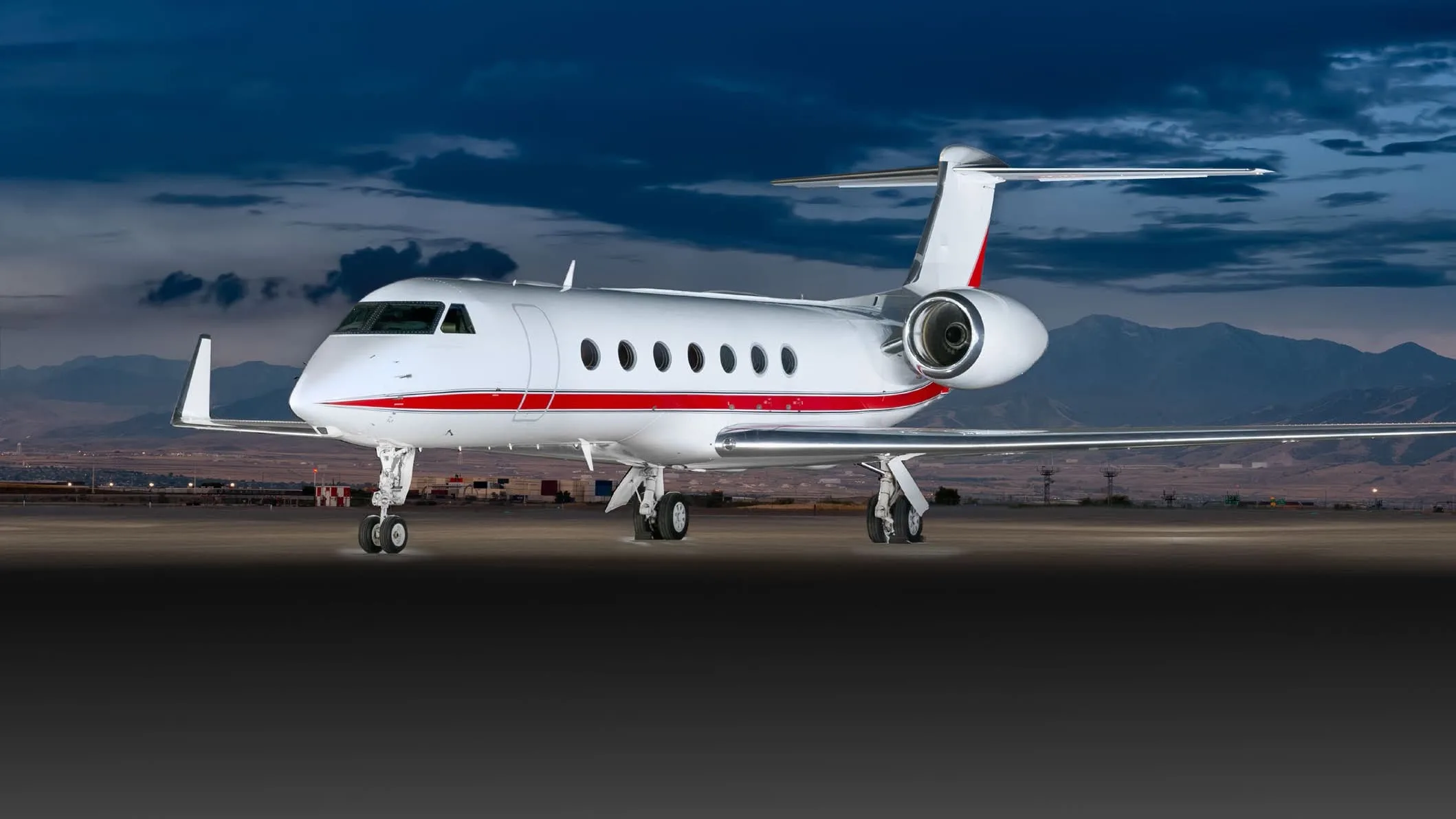 A white business jet with blue accents, registration N750CR, parked on an tarmac in front of a white hangar.