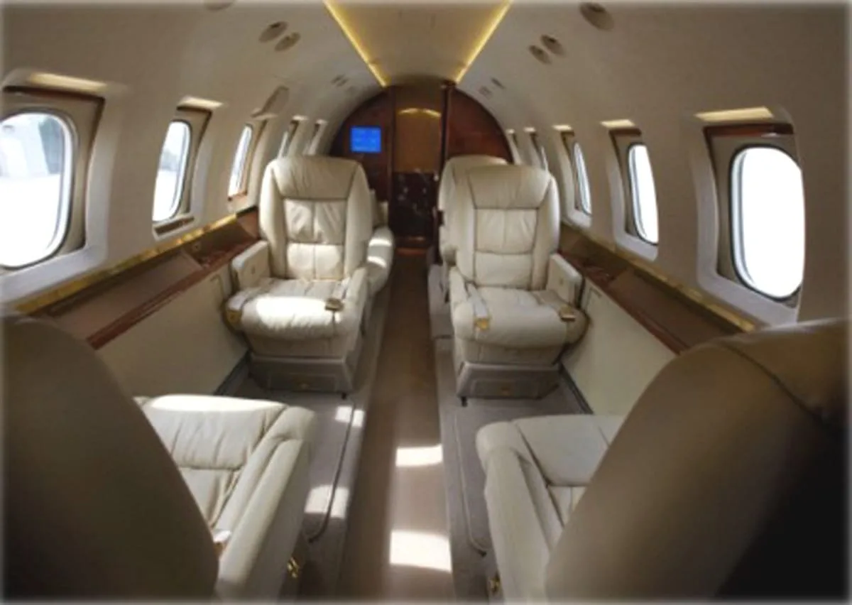 The luxurious interior cabin of a private jet with beige leather seats.