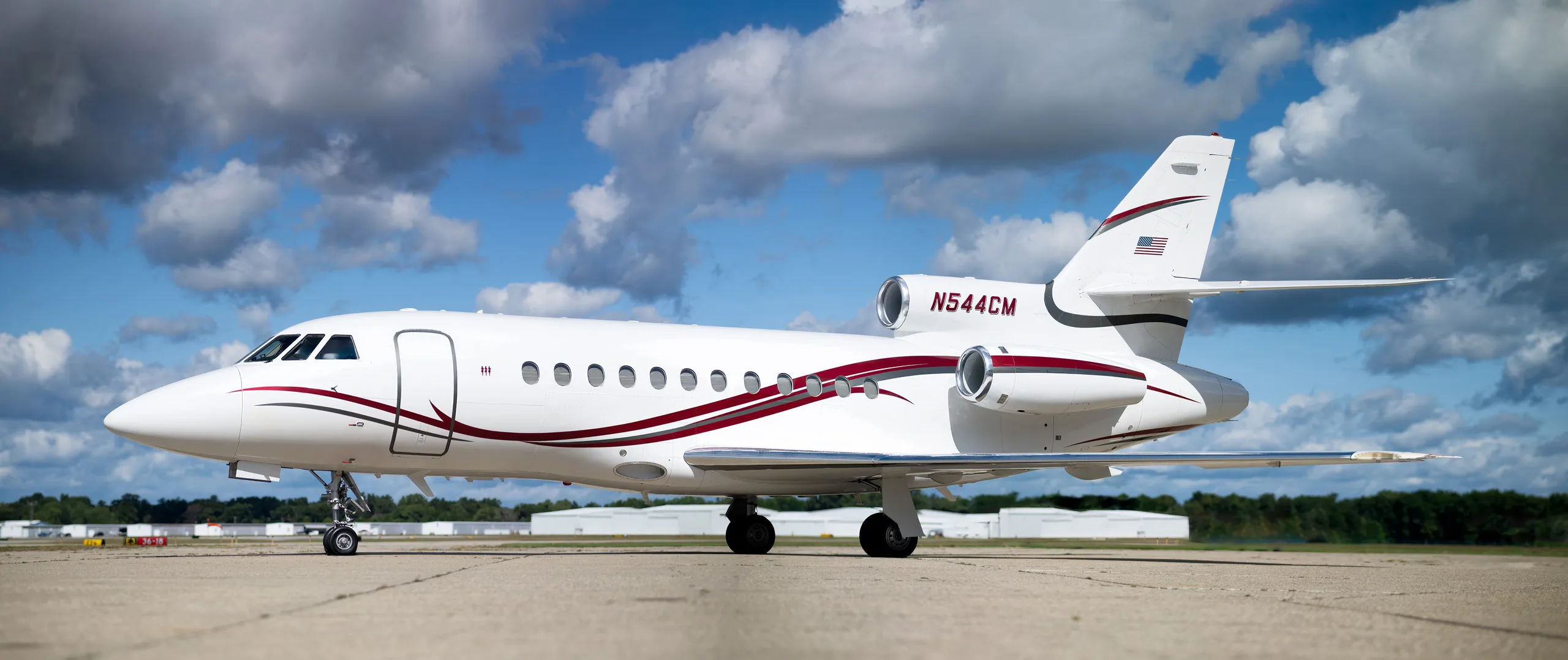 Side view of a white aircraft with red stripes on the tarmac.