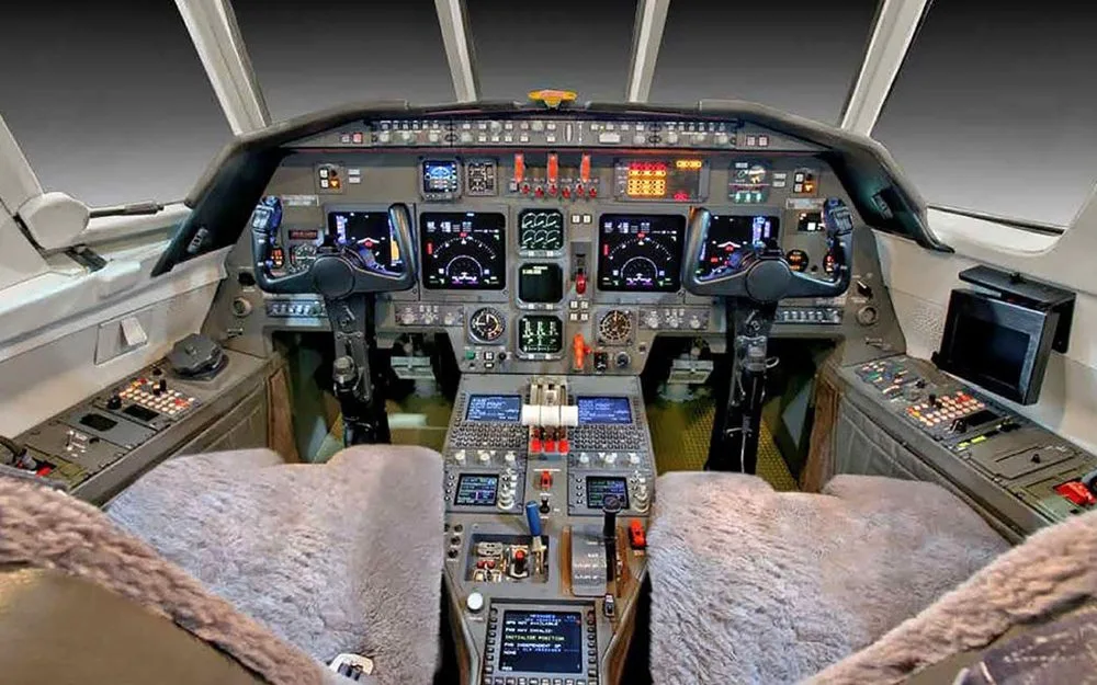 The modern cockpit of a business jet featuring multiple digital displays and control yokes.