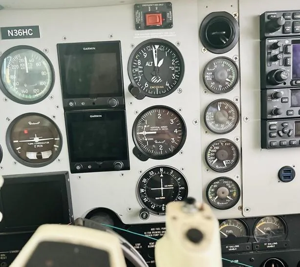 The instrument panel of the N36HC cockpit, featuring analog gauges and two Garmin digital displays.