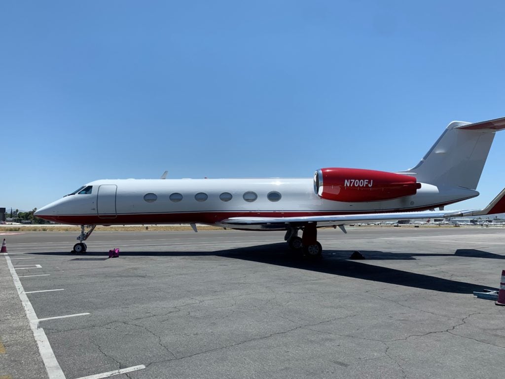 Side view of a white aircraft with red accents on the tarmac.