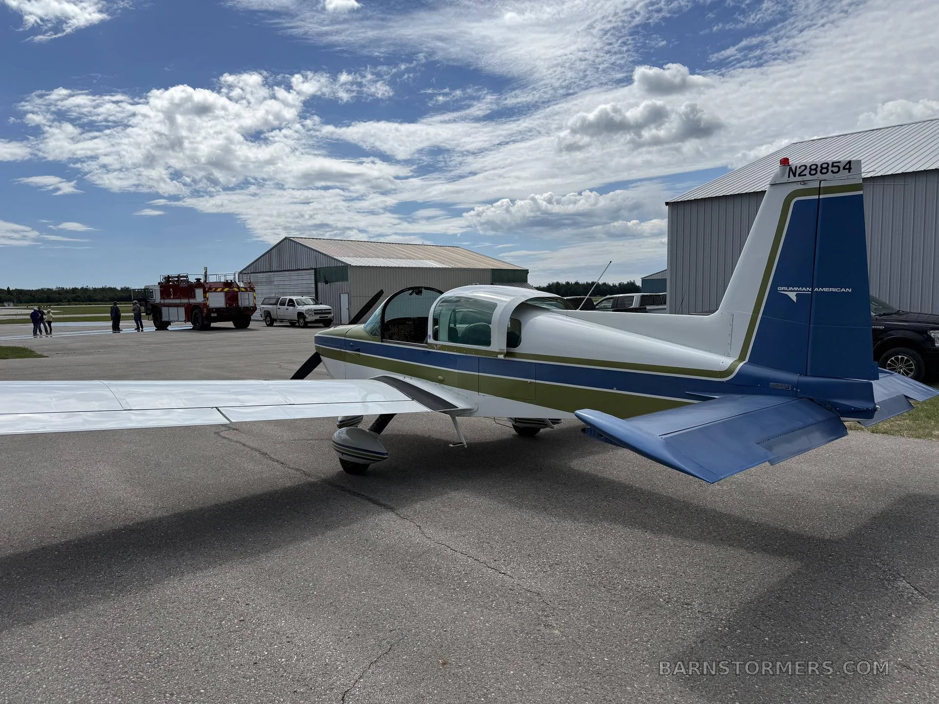 A rear-side view of a Grumman American aircraft with tail number N28854, parked on an airfield.