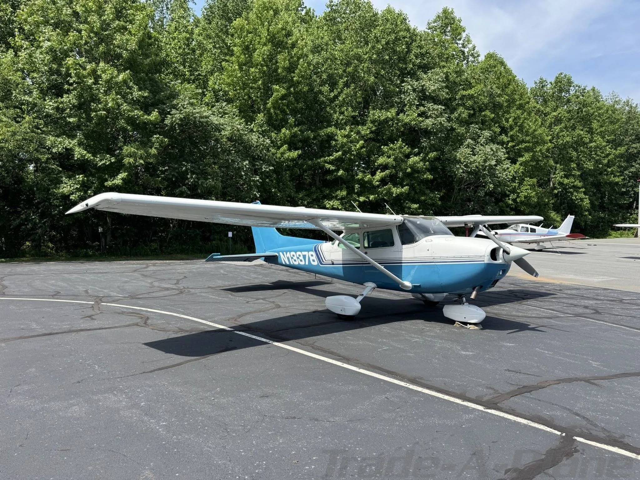 A front-right view of the blue and white Cessna 172 Skyhawk (N13378) parked on an asphalt apron.