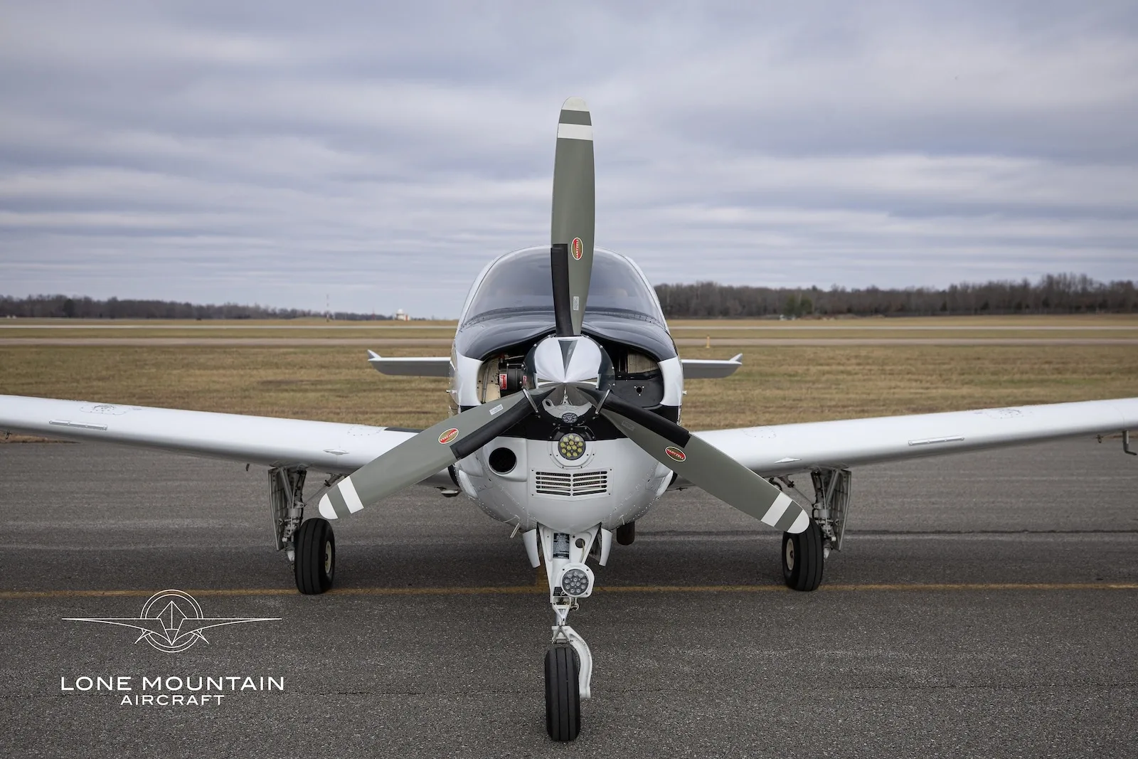 A head-on view of the N721EN single-engine propeller aircraft, showing its propeller and nose landing gear on an airfield.