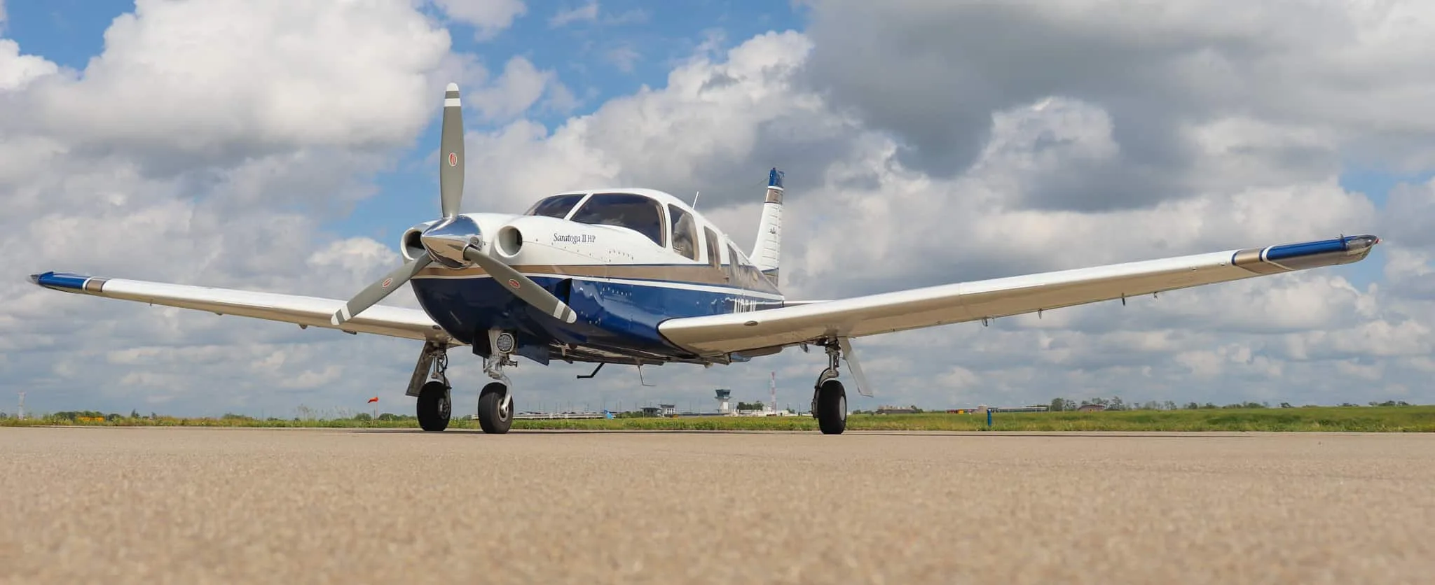 A low-angle front view of the Piper Saratoga II HP aircraft, N954K, showcasing its full wingspan on an airfield.