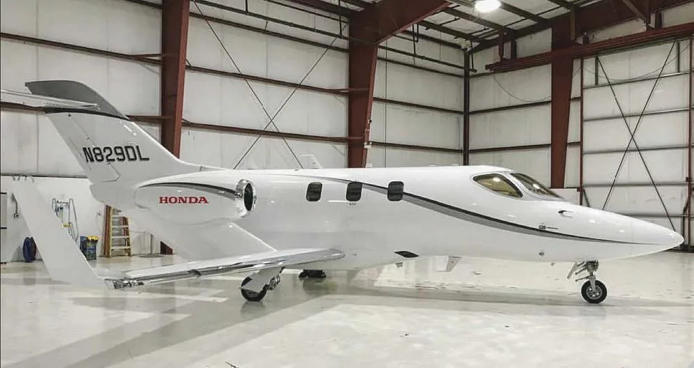 A white HondaJet with registration N829DL is parked inside a hangar.