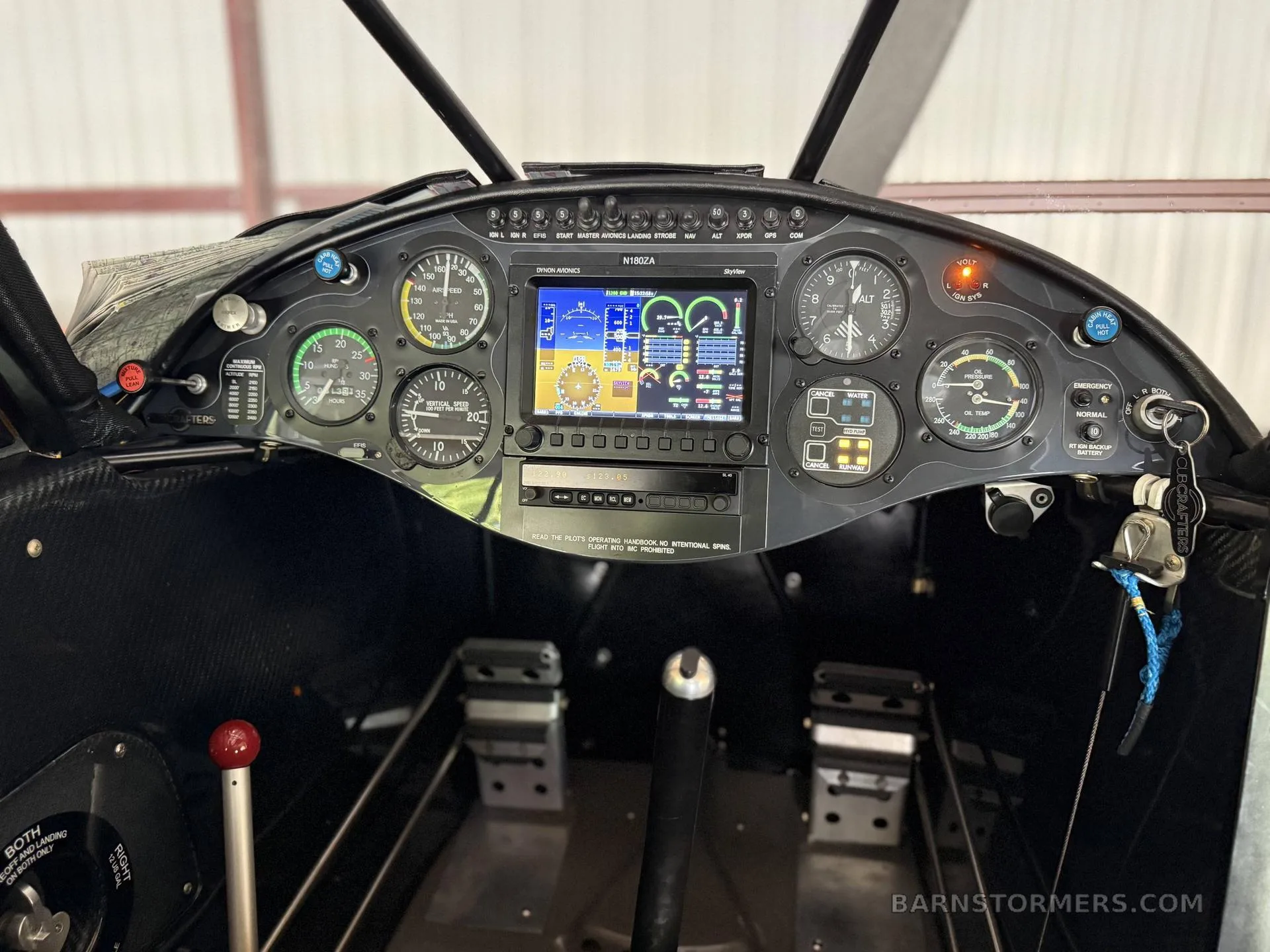 The cockpit instrument panel of an aircraft, featuring analog gauges and a central digital display showing flight data.