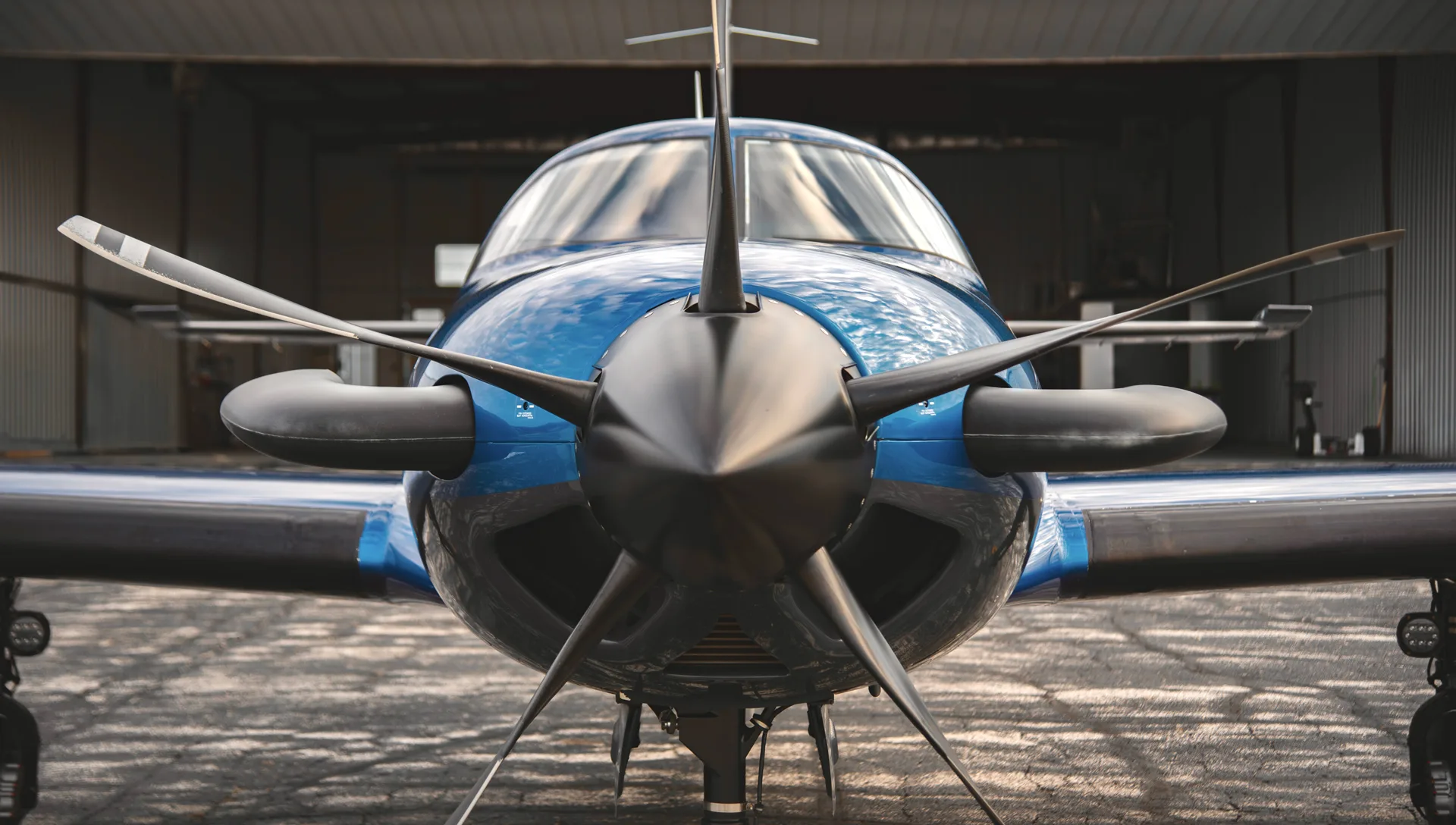 A close-up of the front of the blue and black M700 aircraft with the propeller in focus.