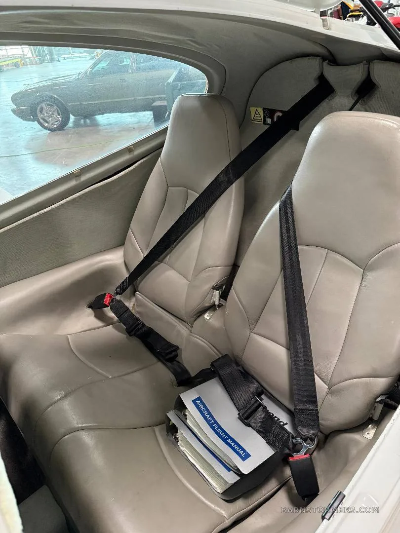 The rear two grey leather seats of the aircraft cabin, with an aircraft flight manual on the seat.