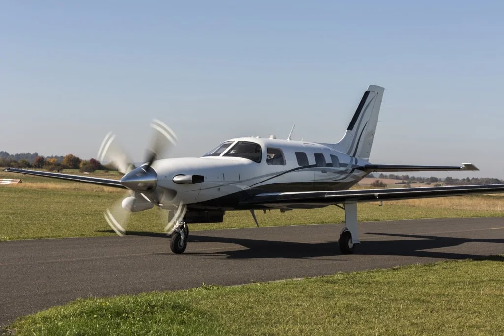 Front side view of a white and gray turboprop aircraft on the runway.